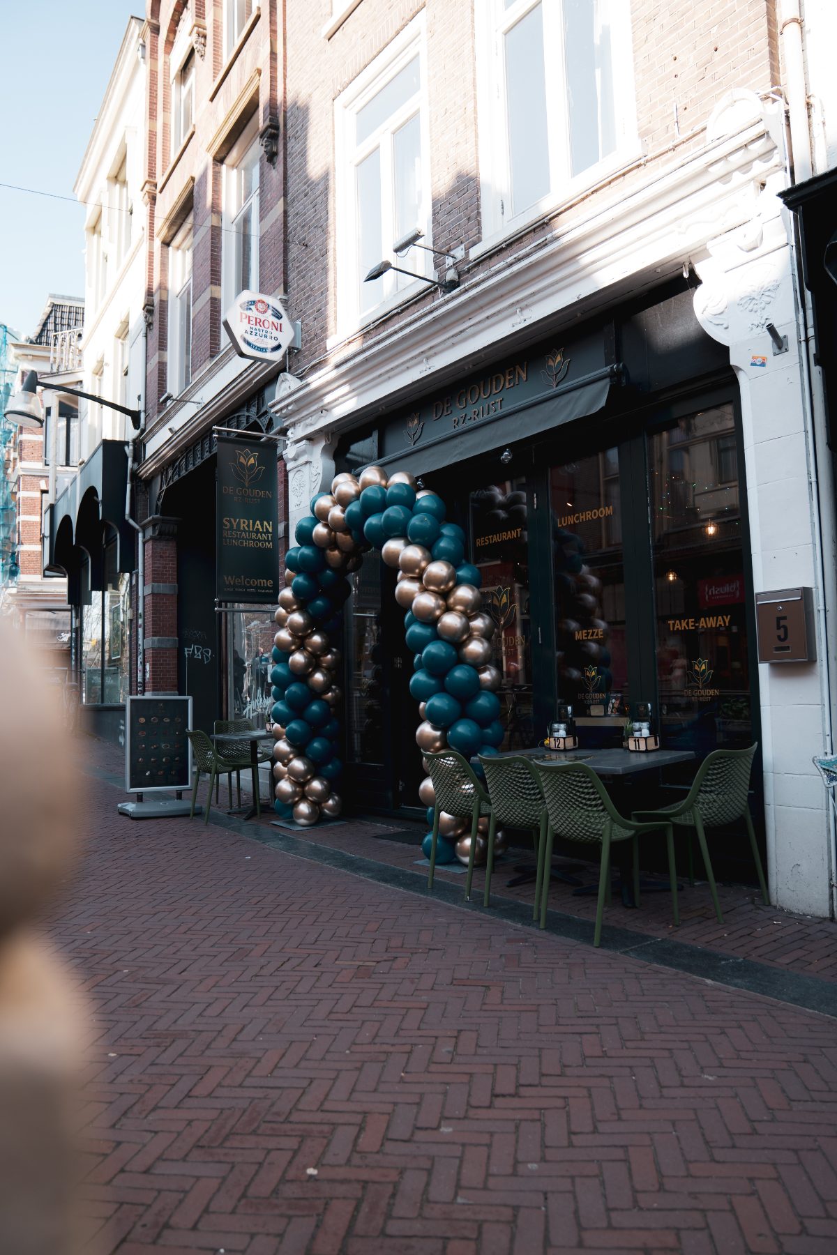 De gevel aan het Naauw met teal-gouden boog